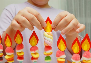 Child hands putting a paper flame clipart