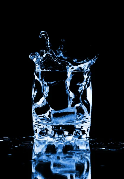 Крижаний куб розбризкується у склянку води — стокове фото