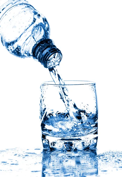 Agua salpicando de botella en vidrio —  Fotos de Stock