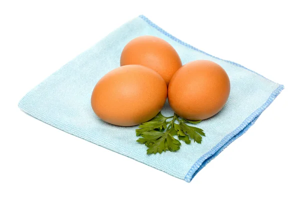 Kahverengi yumurta ve mavi peçete üzerine maydanoz — Stok fotoğraf