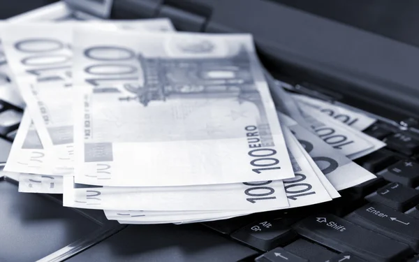 Billetes en euros en el portátil — Foto de Stock