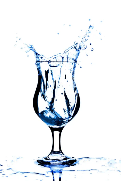 Ice cube splashing into glass of water — Stock Photo, Image