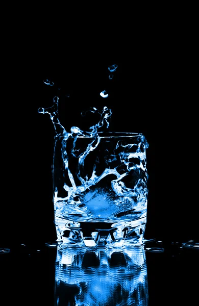 Ice cube stänk i glas vatten — Stockfoto