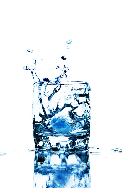 Ice cube splashing into glass of water — Stock Photo, Image