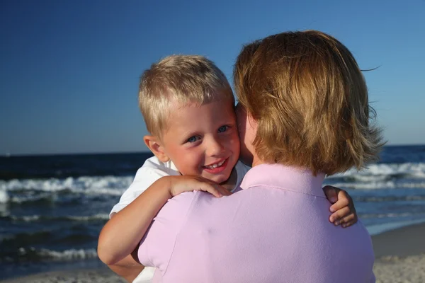 Mãe abraçando filho em uma praia — Fotografia de Stock