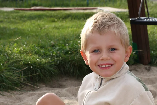 Jonge jongen glimlachen op een speelplaats — Stockfoto