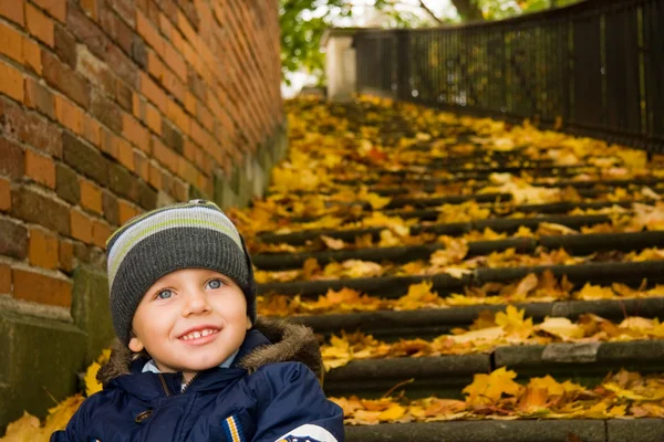 Pojken sitter på trappan i park — Stockfoto