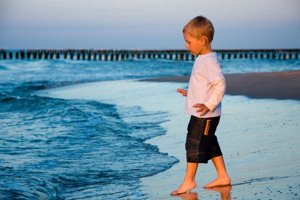Boy going to sea in sunset — Stock Photo, Image
