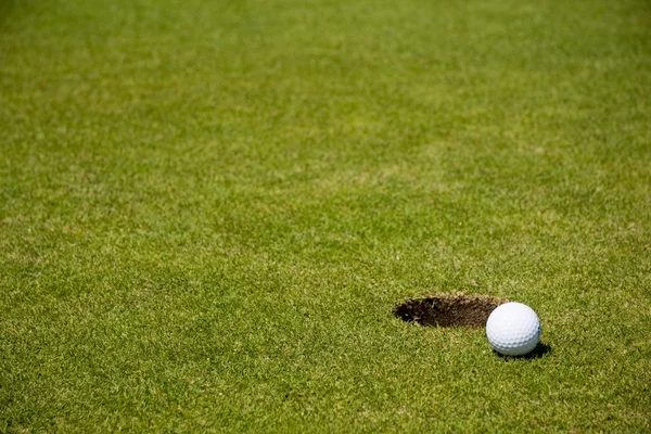 Гольф мяч рядом с лункой — стоковое фото