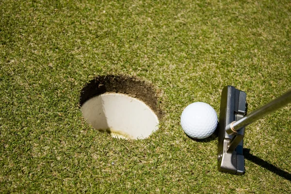 Mettre une balle de golf dans un trou — Photo