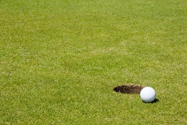 Гольф мяч рядом с лункой — стоковое фото