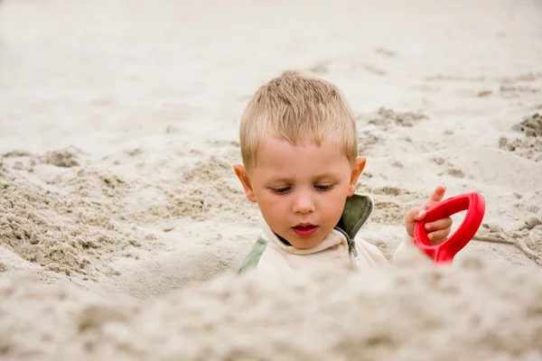 Jongen graven in zand op strand — Stockfoto