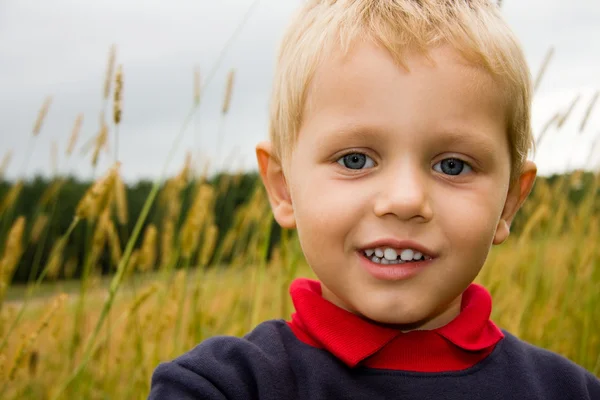 Хлопчик посміхається на полі на відкритому повітрі — стокове фото