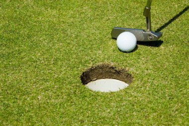 Putting golf ball to a hole clipart