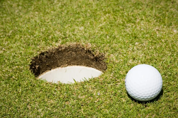 Bola de golfe perto de um buraco — Fotografia de Stock