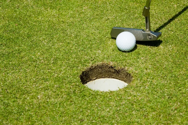Положить мяч для гольфа в лунку — стоковое фото