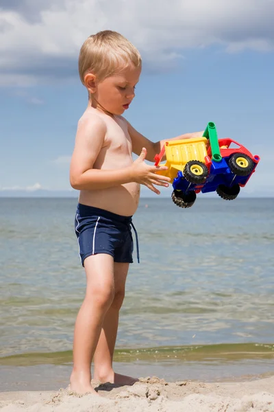 Jongen met speelgoedauto op strand — Stockfoto