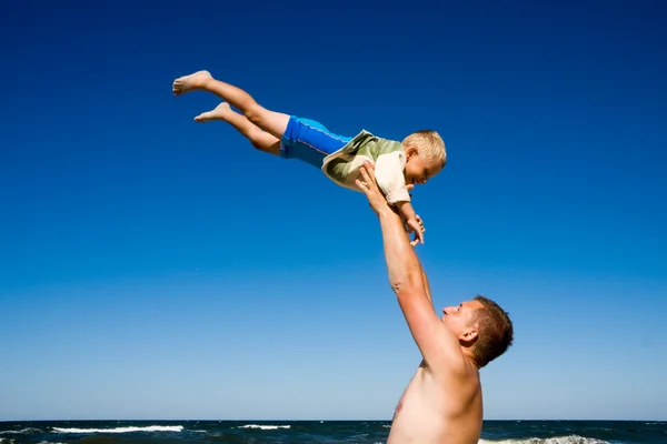 Father throwing son on beach — Stock Photo, Image