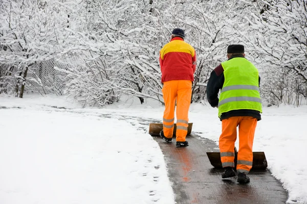 Arbeiter räumen ersten Schnee Stockbild