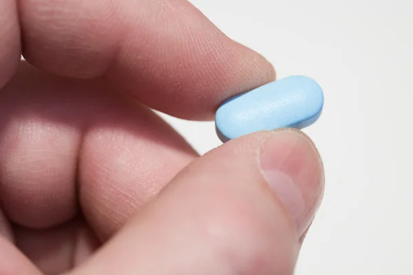 Palce, niebieska tabletka — Zdjęcie stockowe