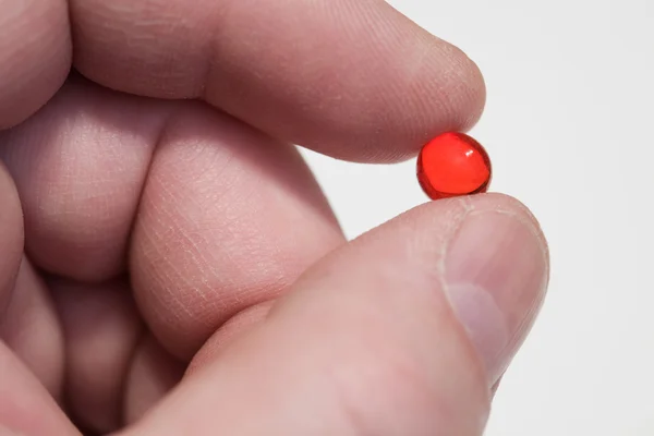 Пальцы, красная таблетка — стоковое фото