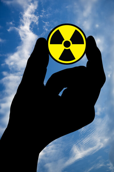 Hand with radiation sign and sky