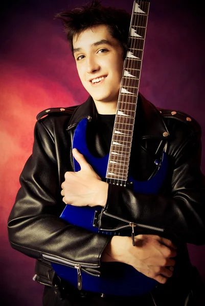 Schöner junger Mann umarmt seine Gitarre — Stockfoto