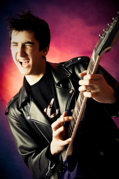 Podekscytowany młody mężczyzna gra na gitarze — Zdjęcie stockowe