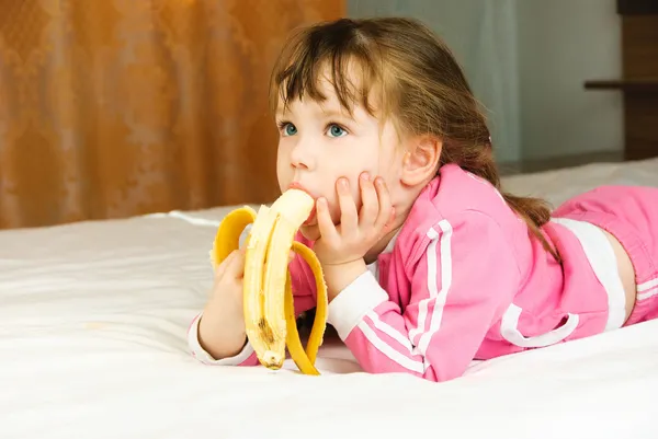 Pikkutyttö syö banaania. — kuvapankkivalokuva