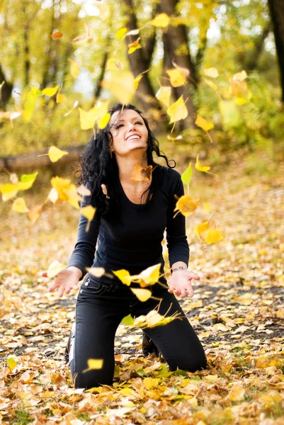 Dziewczyna bawi sie z żółtymi liśćmi — Zdjęcie stockowe
