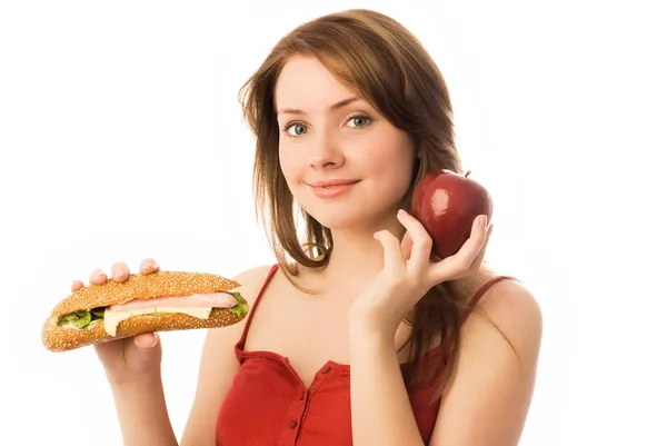 Jovem mulher escolhendo entre uma maçã e quente fazer — Fotografia de Stock
