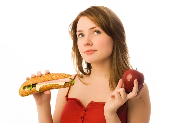 Красивая девушка выбирает между яблоком и горячим — стоковое фото