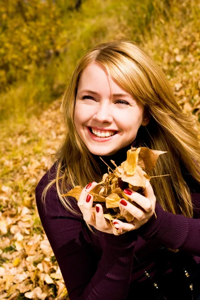 Linda chica con hojas amarillas en las manos — Foto de Stock