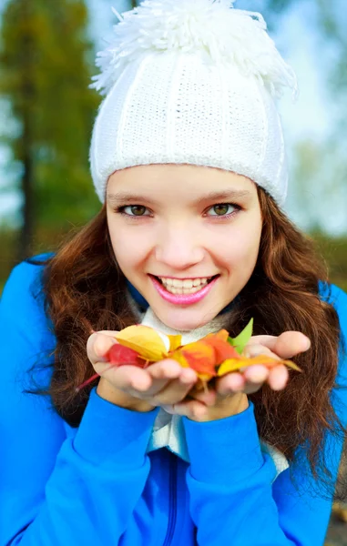 Ładna dziewczyna z żółtymi liśćmi w jej ręce — Zdjęcie stockowe