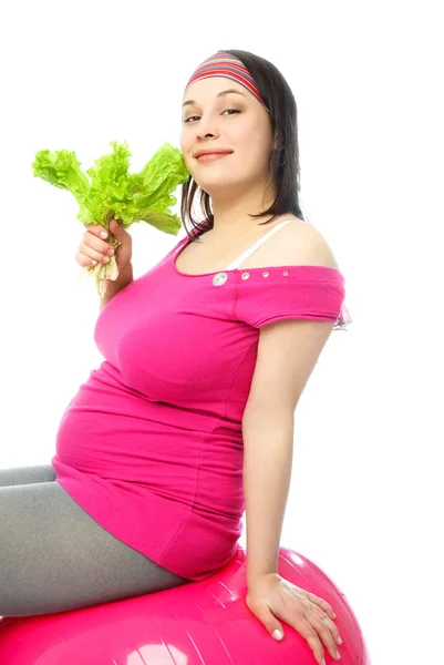 Mujer embarazada en la pelota de fitness comer salat — Foto de Stock