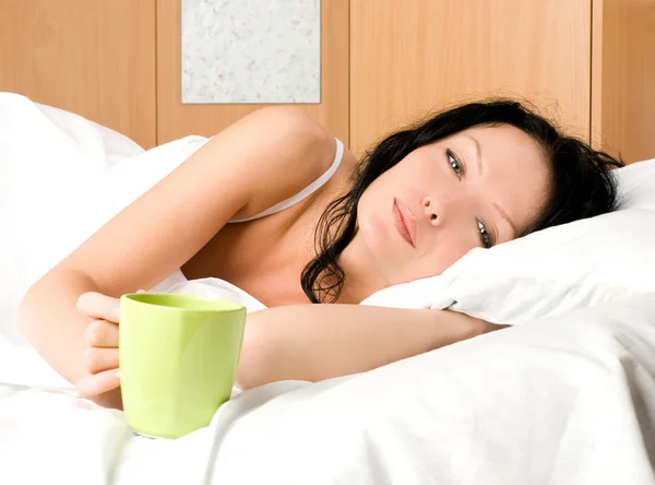 Όμορφη γυναίκα με ένα φλιτζάνι καφέ στο κρεβάτι — Φωτογραφία Αρχείου