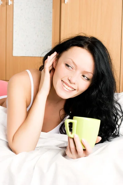 Κορίτσι με ένα φλιτζάνι καφέ στο κρεβάτι — Φωτογραφία Αρχείου