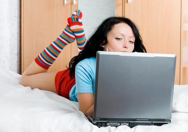 Nachdenkliche Brünette Mädchen mit einem Laptop auf dem be — Stockfoto
