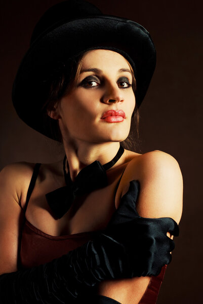 Beautiful young brunette woman wearing a black cylinder hat, a smoking jacket and a butterfly bow tie