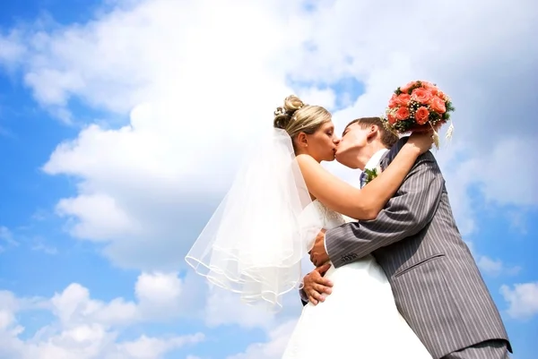 Жених и невеста целуются на фоне голубого неба — стоковое фото