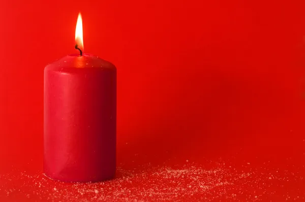 Рождественская свеча на красном фоне — стоковое фото