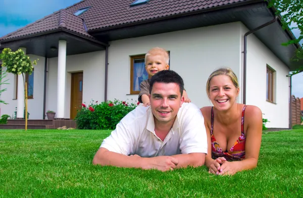Família feliz na frente da casa — Fotografia de Stock