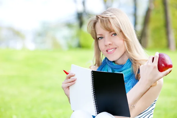 Pretty girl studying on a green meadow — Stock Photo, Image