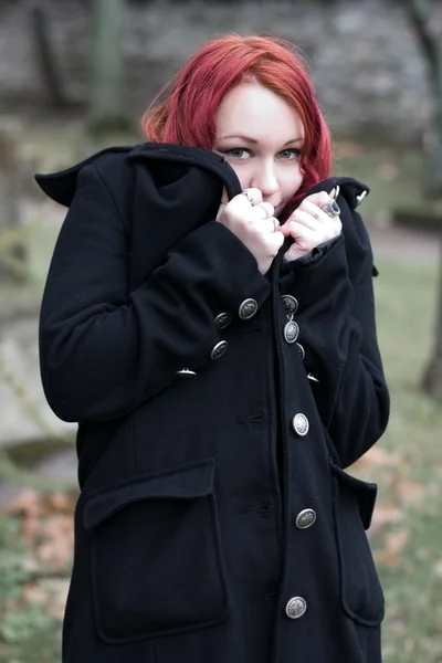 Pelirroja coqueta chica gótica en un abrigo negro — Foto de Stock