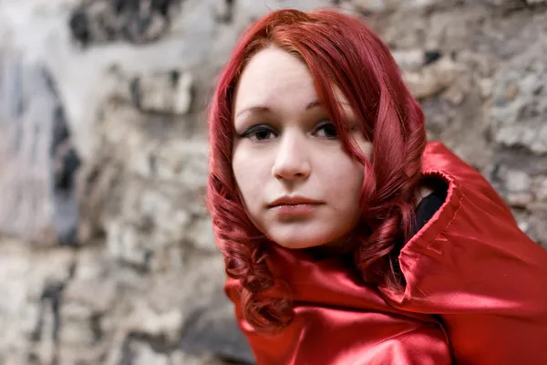 Roodharige meisje met rode satijnen mantel — Stockfoto