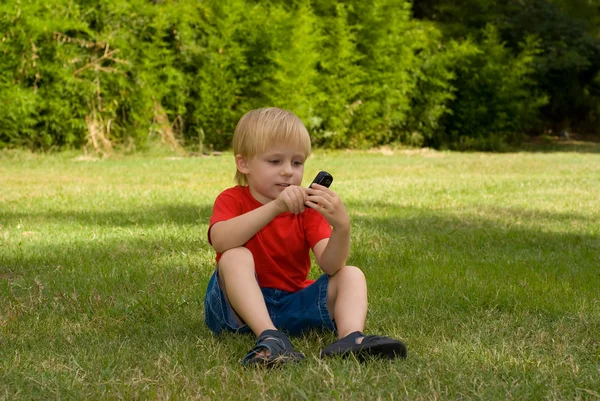Το μικρό αγόρι που κάθεται σε ένα χόρτο — Φωτογραφία Αρχείου