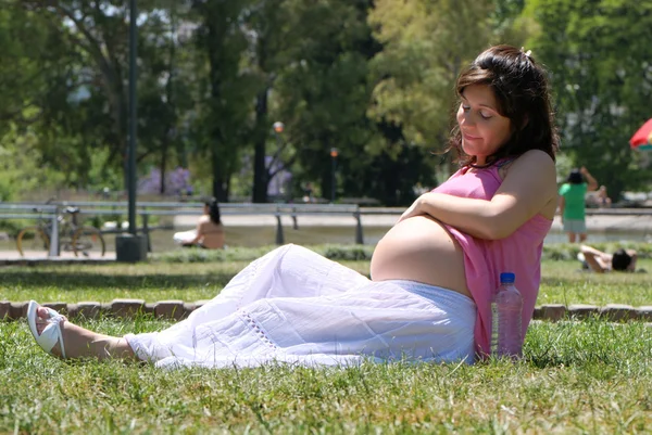 Беременная счастливая молодая женщина в парке — стоковое фото