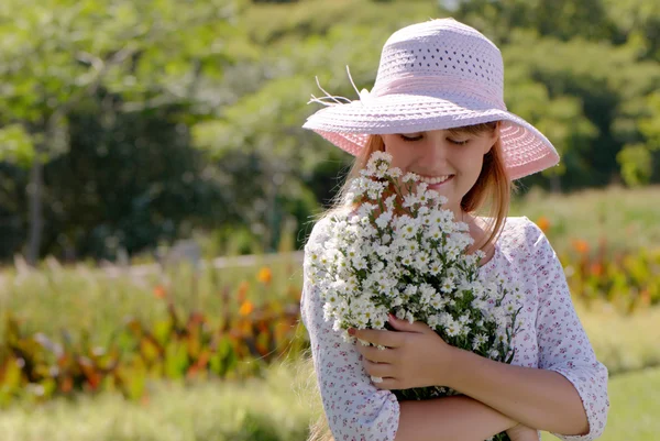 Дівчина в капелюсі з купою квітів — стокове фото