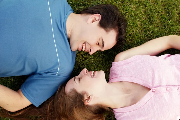 Jeune, un couple aimant couché sur une herbe — Photo