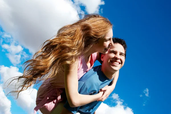 Счастливая молодая пара против неба — стоковое фото